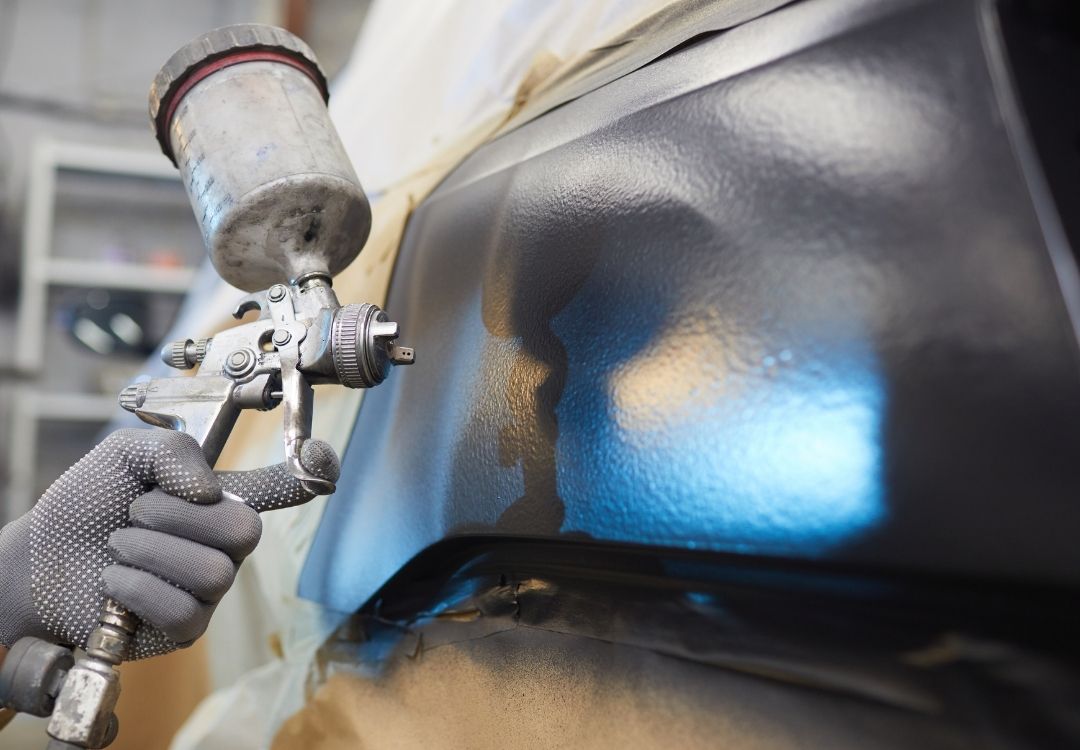 Technician painting a car using a spray machine